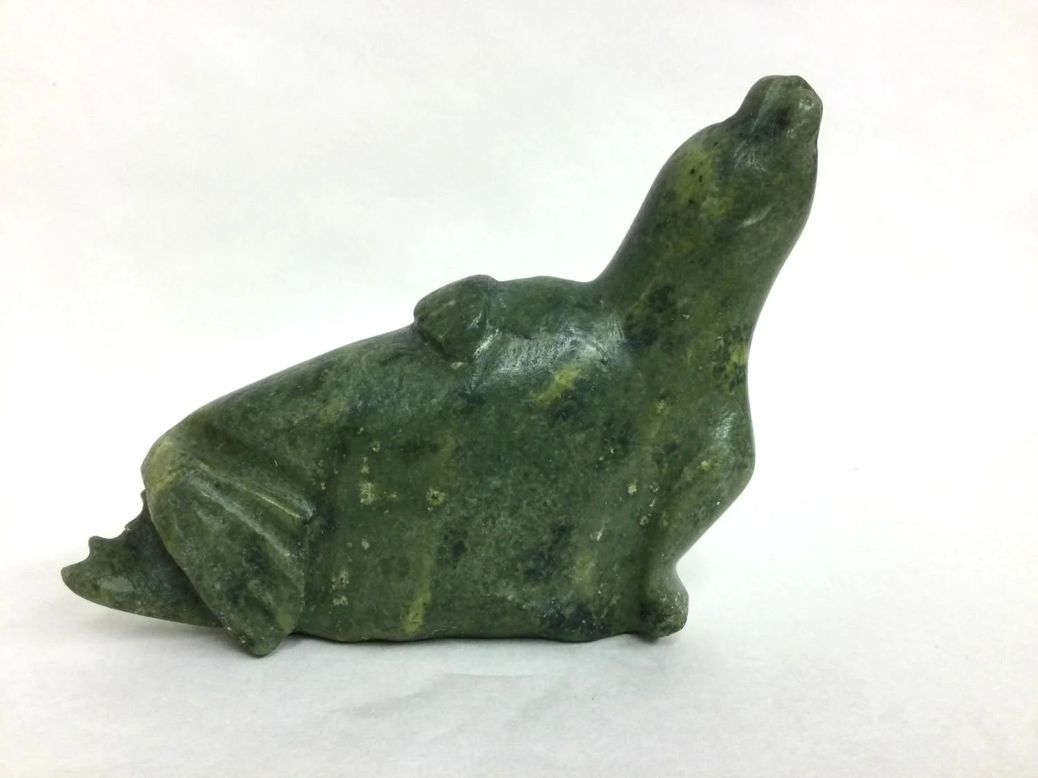 Koomwartok Ashoona (E7-1102) 1930-84 Kinngait/Cape Dorset, ᑭᙵᐃᑦ, Seal (#25.9.11), early 1960s, green serpentine, 5 x 9 x 2 inches (13 x 23 x 5 cm), provenance: Saskatchewan Collection, $975 Cdn.