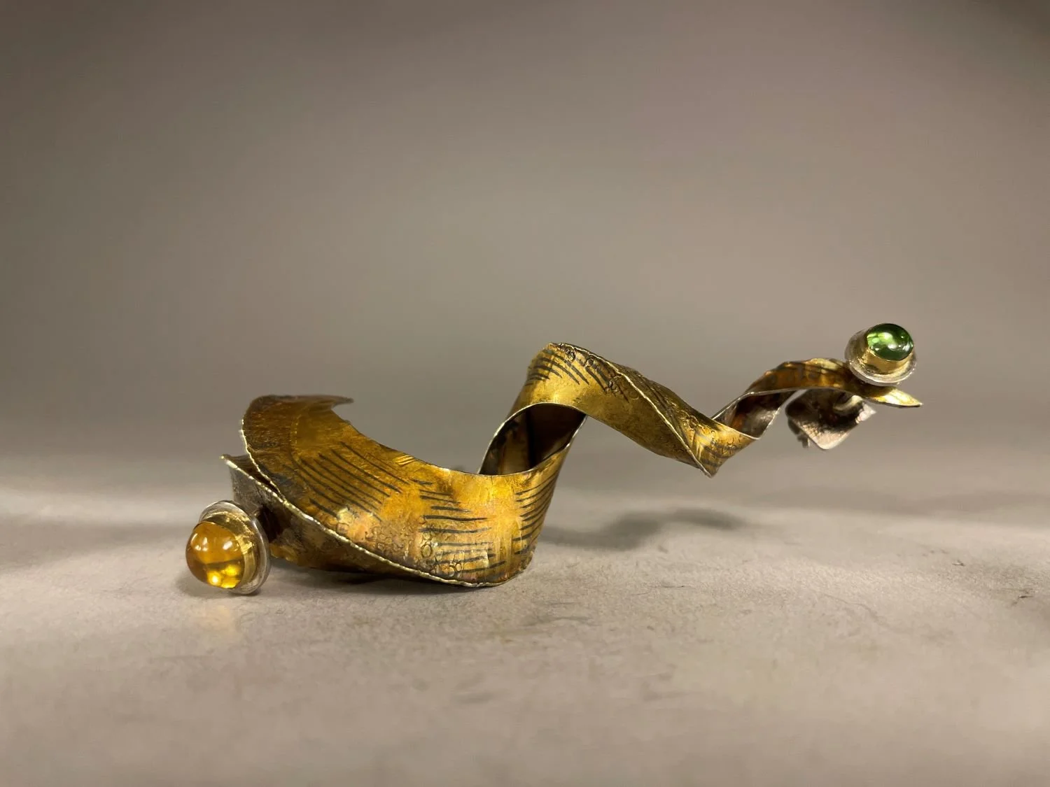 ‘Spirochete’ Brooch (Swoop Series), 1998, materials 18k gold laminate, sterling, 24k Bezels, Citrine, Green Tourmaline, (8.7x3x2.8 cm), $1800 Cdn.