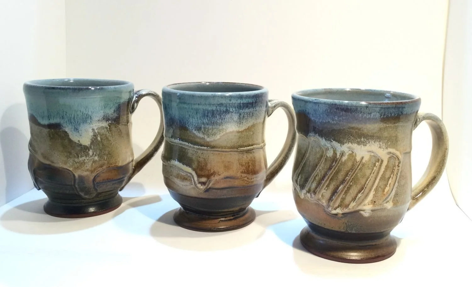 Blue Skies & Prairie Mugs (#26.18jkl), 2026, glazed stoneware, 4.5 x 5 x 3.5 inches (11 x 12.5 x 9 cm), $65 Cdn each. (#1 & 2 sold)