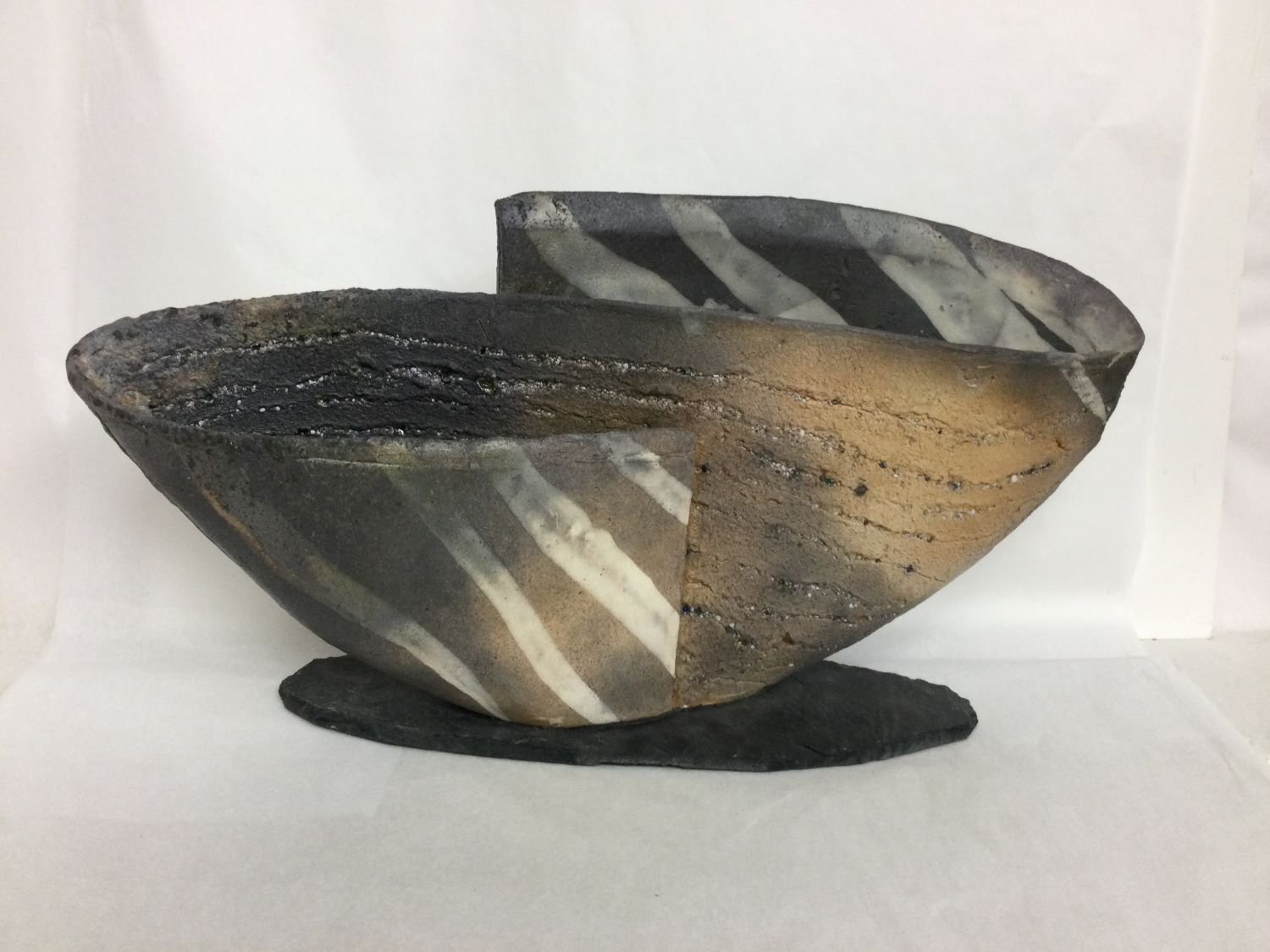 Bowl/Object XXV-VIII, 2025, porcelain slab with slate base, studded with inclusions of natural materials, wood-fired, 8.5 x 17 x 4 inches (21 x 43 x 10 cm), $620 Cdn.