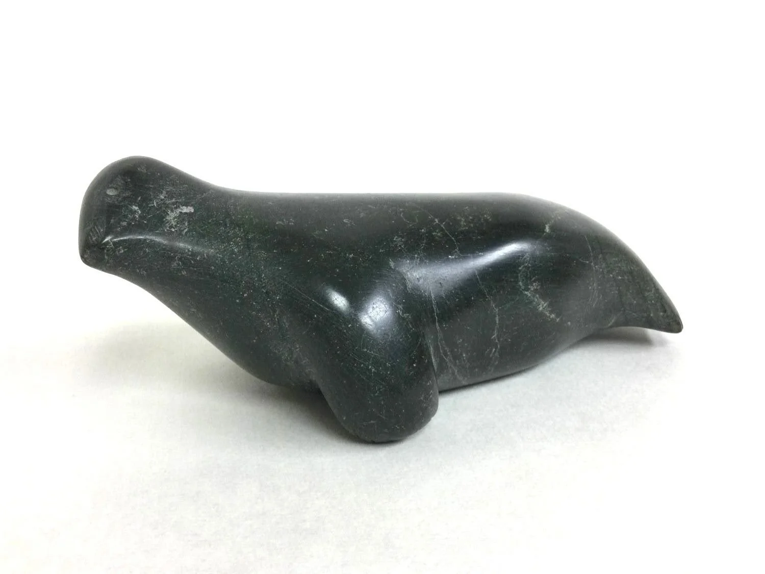 Lucie Eeyaitok Akkuardjuk (E3-625) 1921- Naujaat / Repulse Bay ᓇᐅᔮᑦ, Seal (#25.6.12), n.d., serpentine, 3.25 x 4 x 9 inches (8.5 x 10 x 22.75 cm), provenance: Saskatchewan Collection, $550 Cdn.