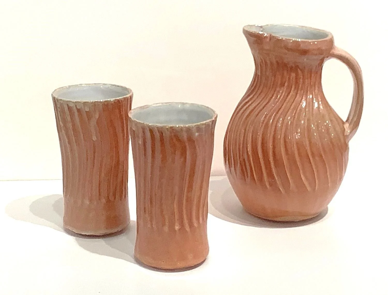 Wave Pitcher and Tumblers (#24.11.40A), 2024, carved porcelain, 8 x 5.5 inches (20.5 x 14 cm) plus 5.5 inch (14 cm) high tumblers, $70 Cdn and tumblers at $40 Cdn each.