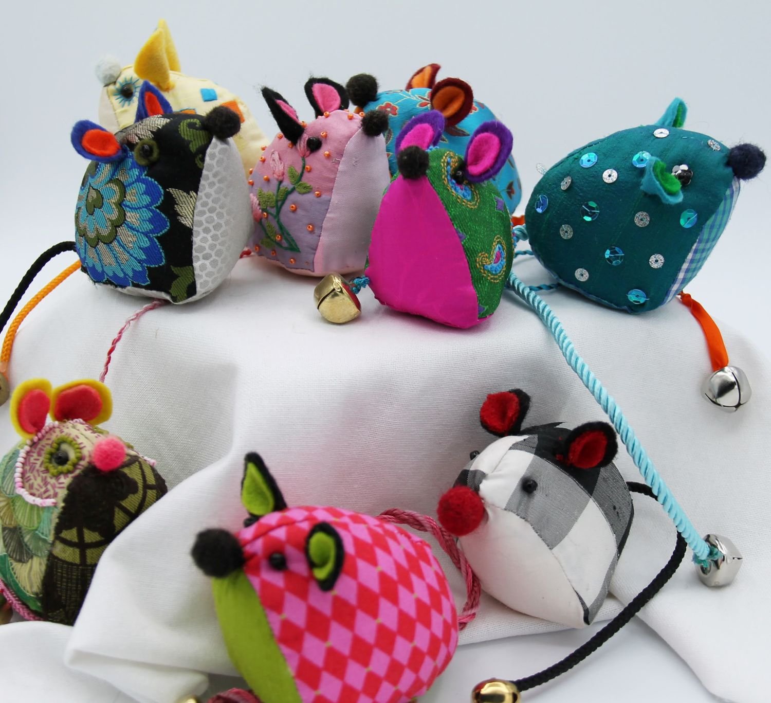 Embroidered Mowzes, 2024, hand embroidered with silk and cotton threads on silk, cotton ground, wool felt, brass bell, 3 x 7.5 x 2.25" (7.5 x 19 x 6 cm), $70 Cdn each.