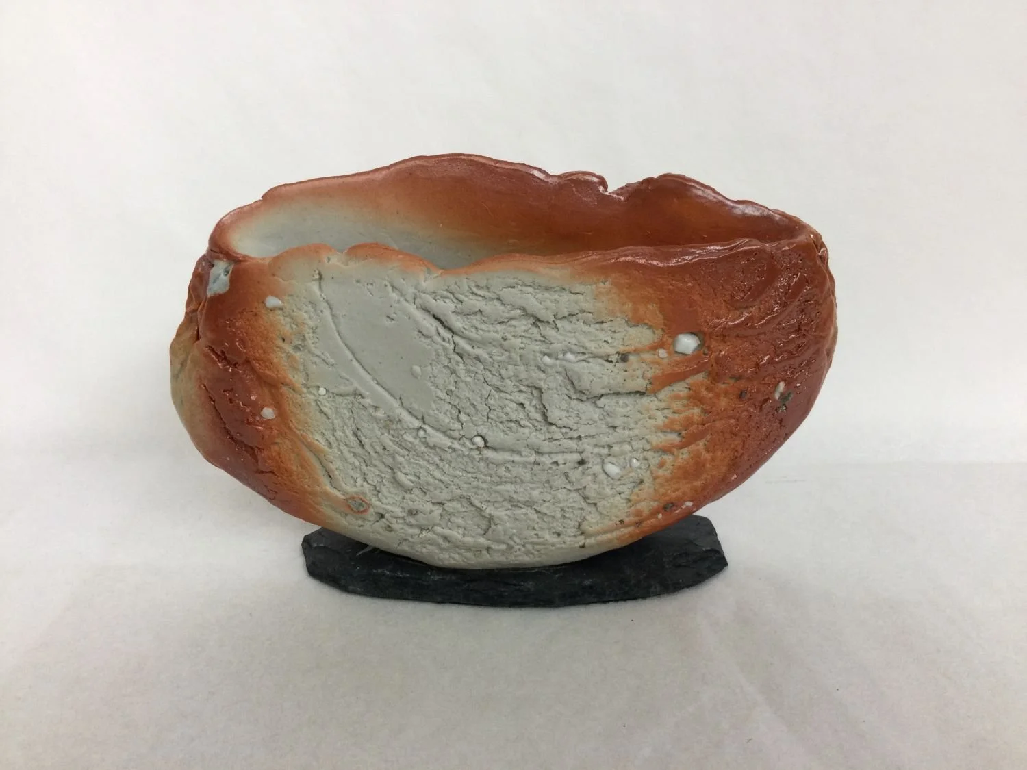 Bowl/Object XXV-VII, 2025, porcelain slab with slate base, studded with inclusions of natural materials, wood-fired, 4 x 6.5 x 1.5 inches (10 x 16 x 3.5 cm), $320 Cdn.