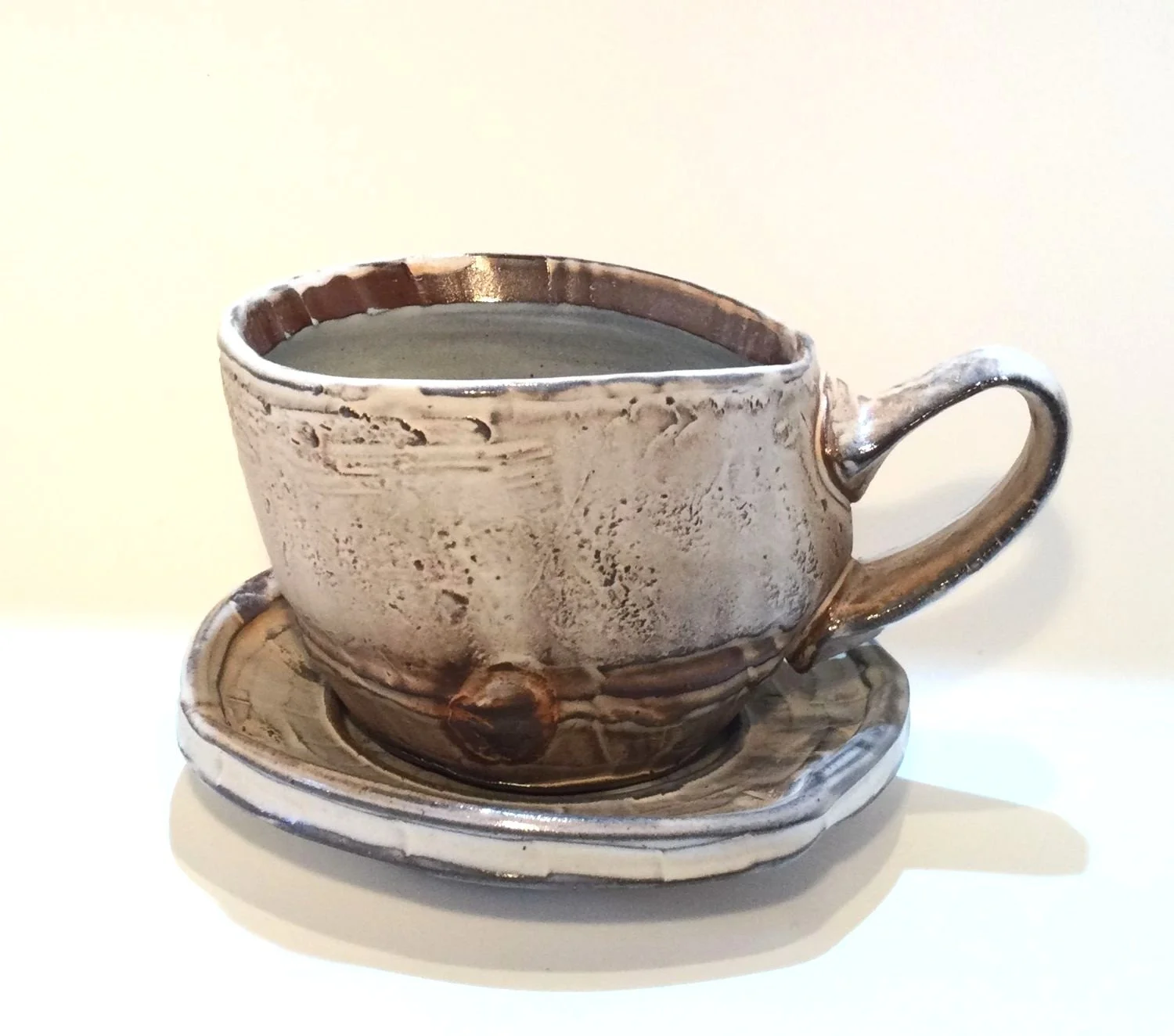 Confluence Mug With Saucer (#26.2.55), 2026, low soda-fired earthenware, 4.5 x 5.5 x 6 inches (11 x 14 x 15 cm), $125 Cdn.