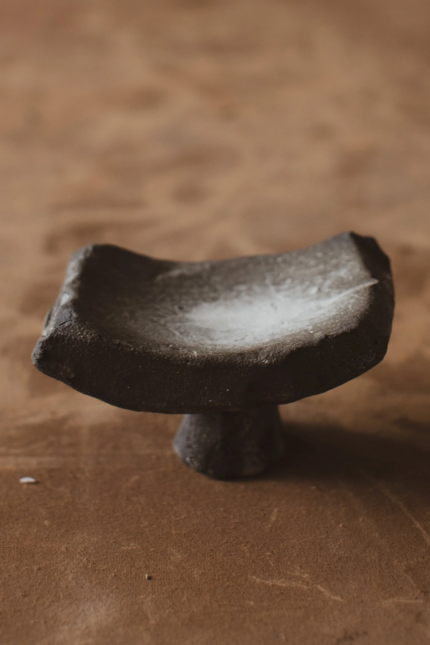 Handmade sculptural ceramic tray on a foot made in dark textured clay with white porcelain finish