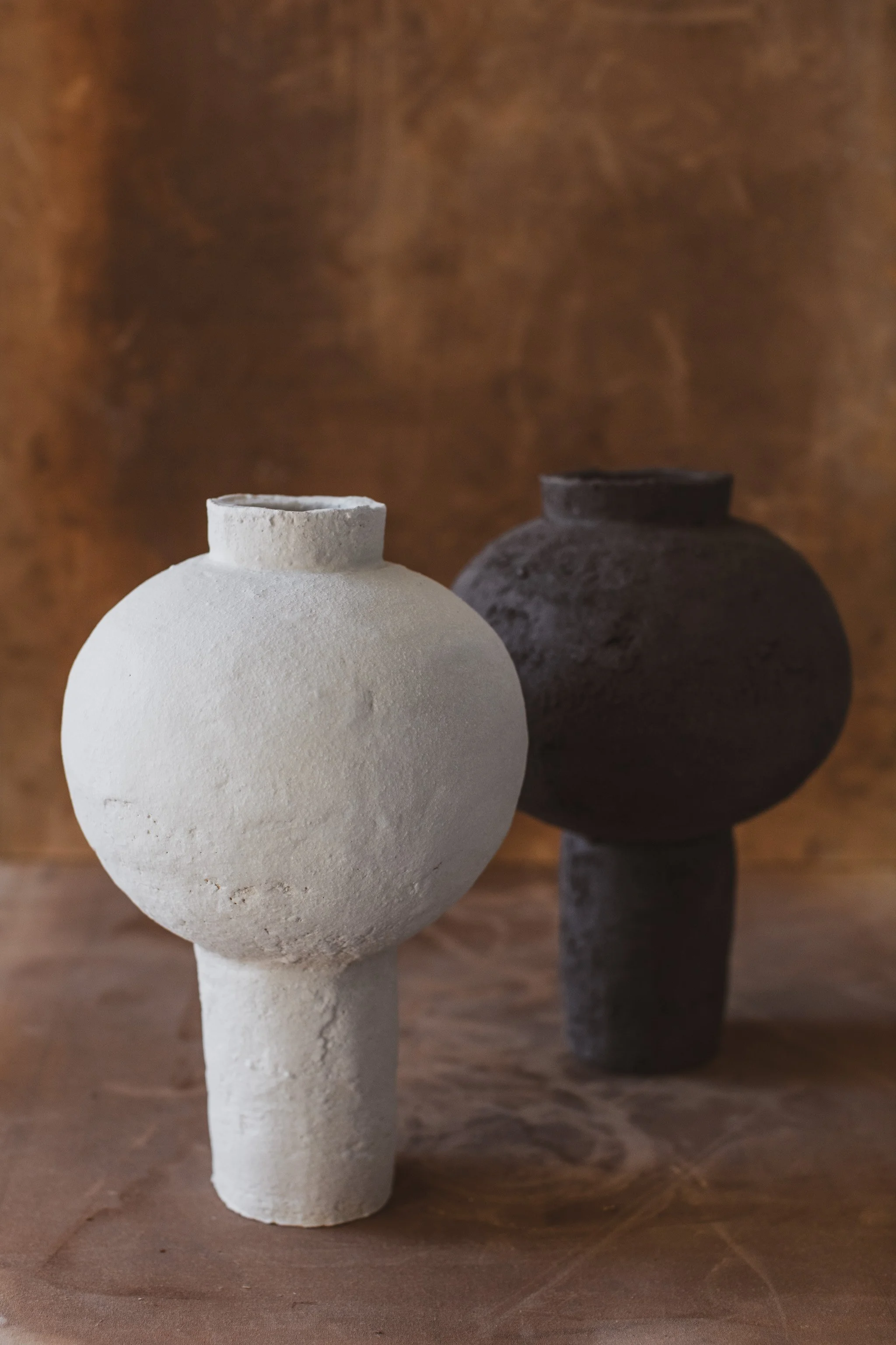 Two handmade ceramic moon jars with textured clay surface in white and black colors