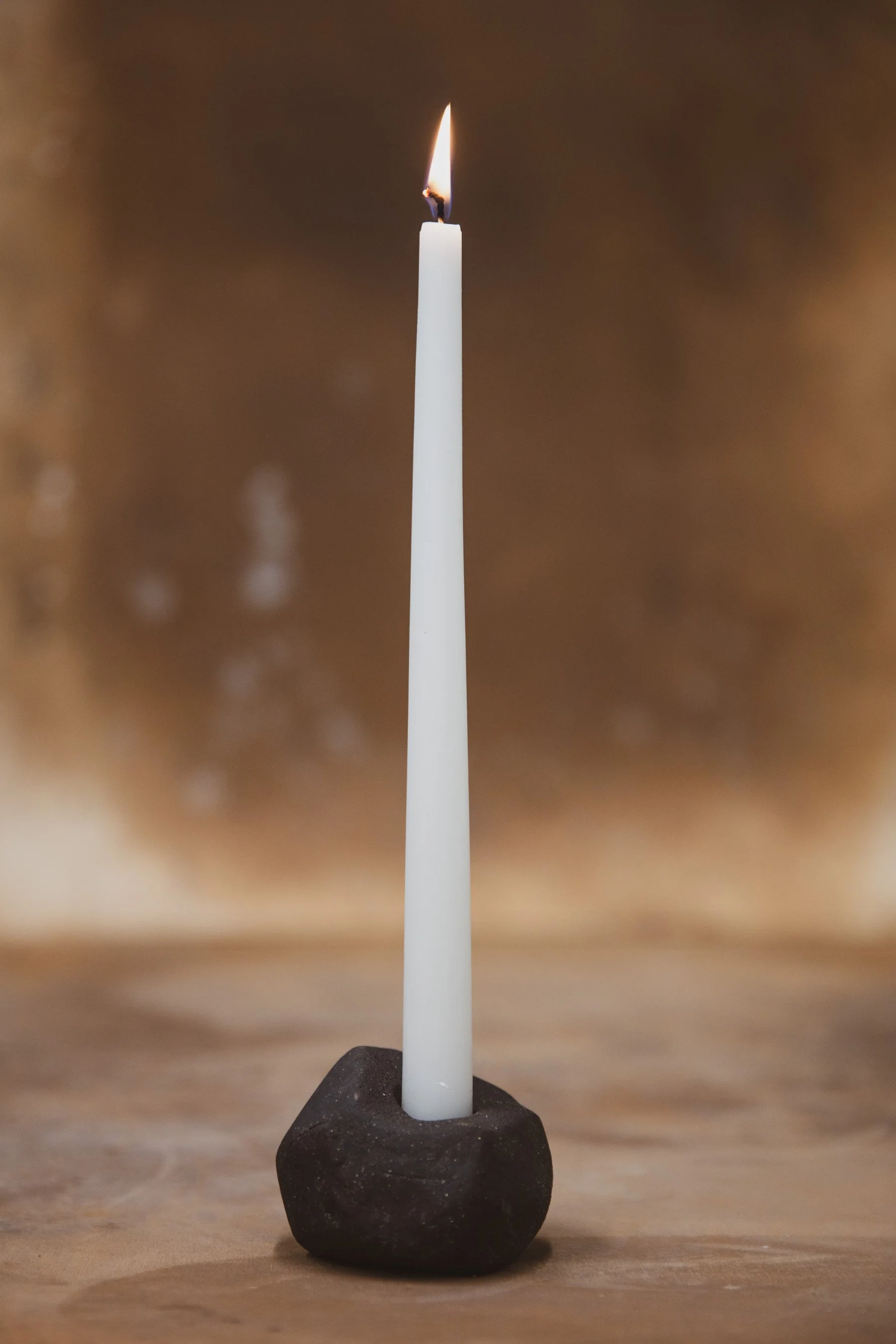 A small black ceramic candlestick holder with a candle