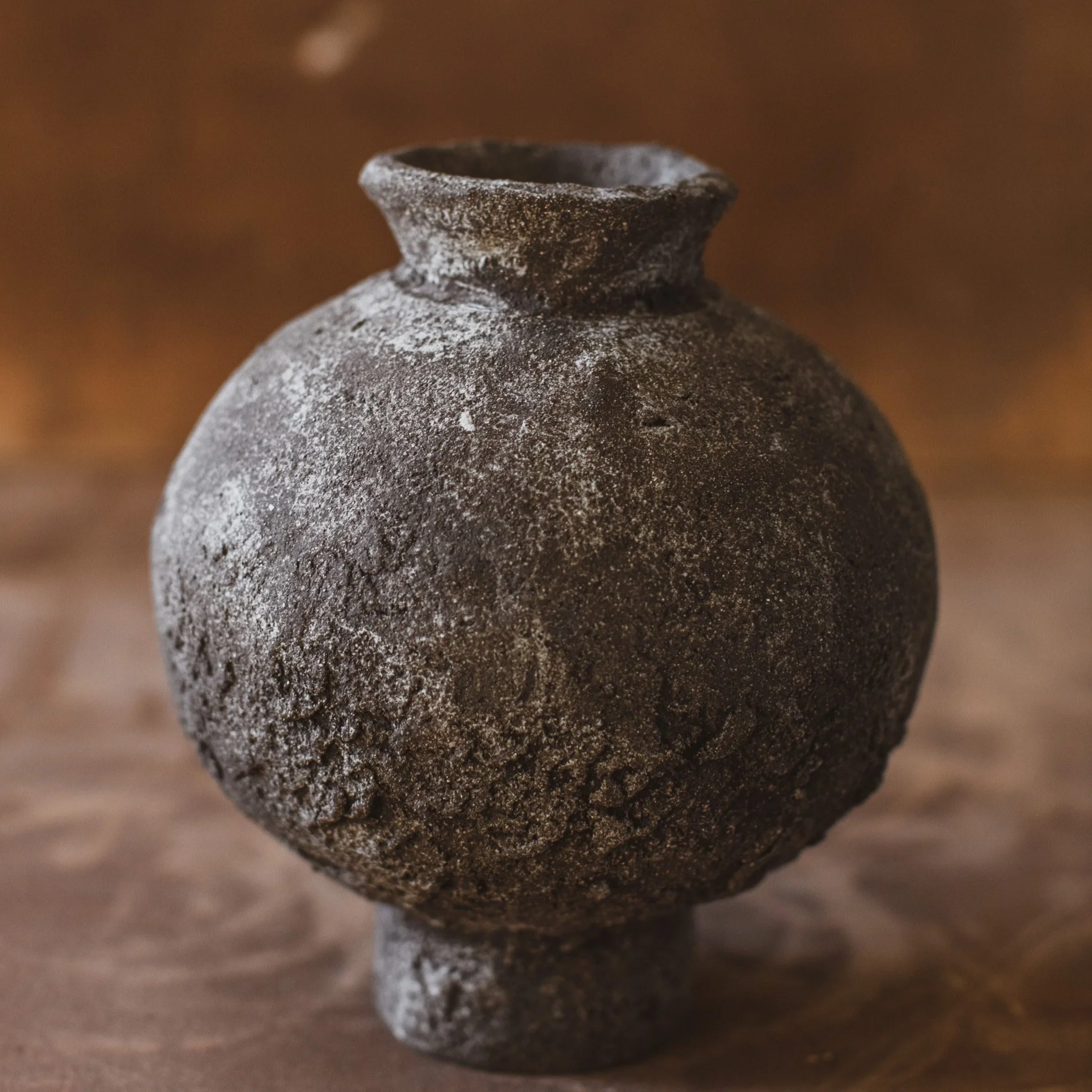 Dark spherical moon jar, natural finish with speckled white porcelain. Ceramic vase has rough exterior.