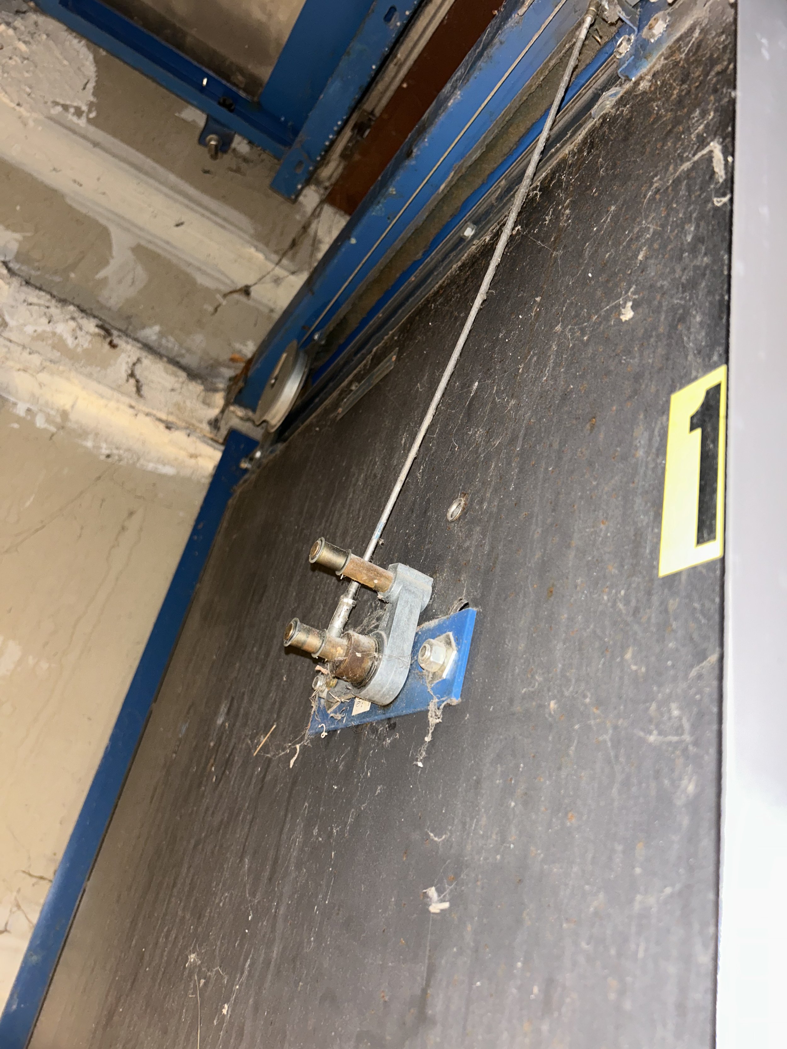 Elevator hoistway with missing door pickup rollers and cobwebs