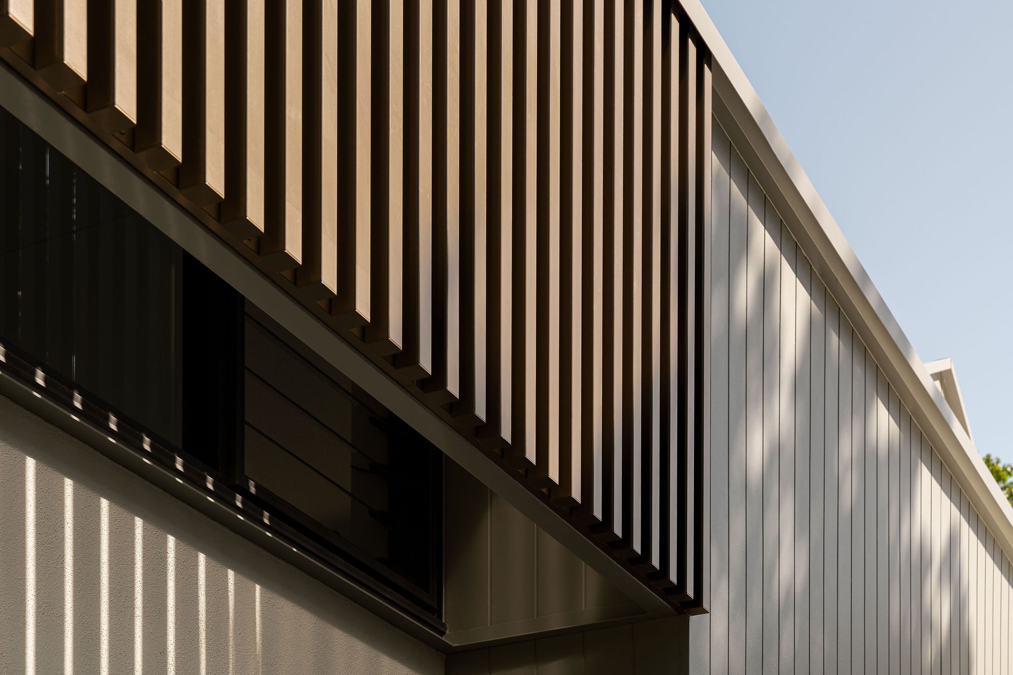 Close-up of vertical timber batten cladding casting rhythmic shadows on the façade of the modern home