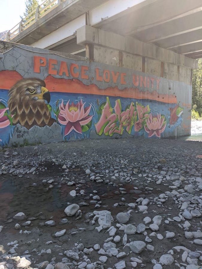  Rock wall mural with painted text "peace love unity" 