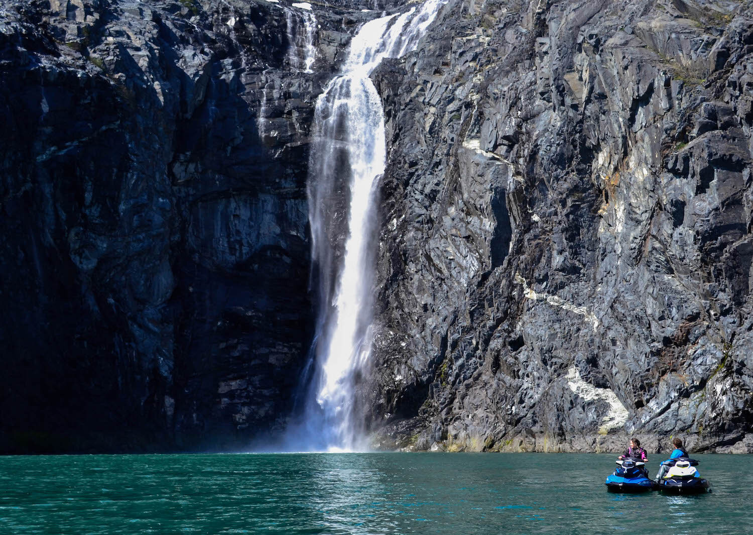  A jet skier next to a large waterfall with Alaska Wild Guides 