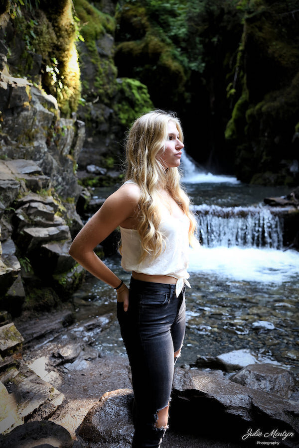  A young lady in a white shirt next to a waterfall with photo taken by Julie Martyn Photography 
