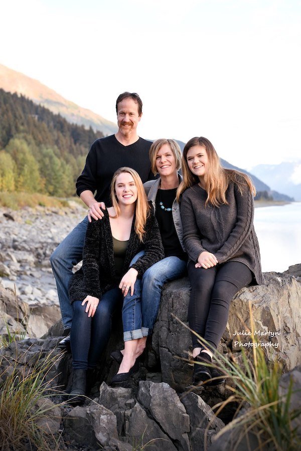  A family of four taking a family portrait next to a rock with photo taken by Julie Martyn Photography 