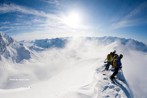  Skiers looking over a cliff they want to ski with Chugach Powder Guide 
