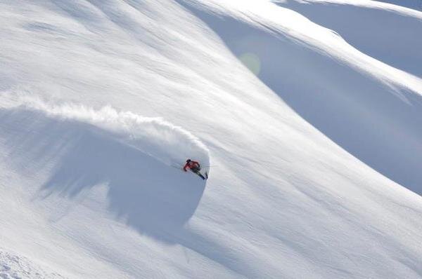  Snowboarder ripping on a big snow field of powder with Chugach Powder Guide 