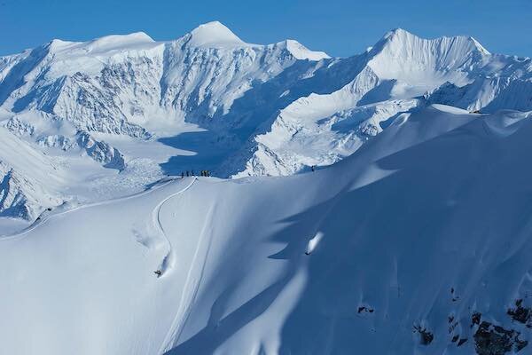  A group skiing down a mountain in Alaska with Chugach Powder Guide 