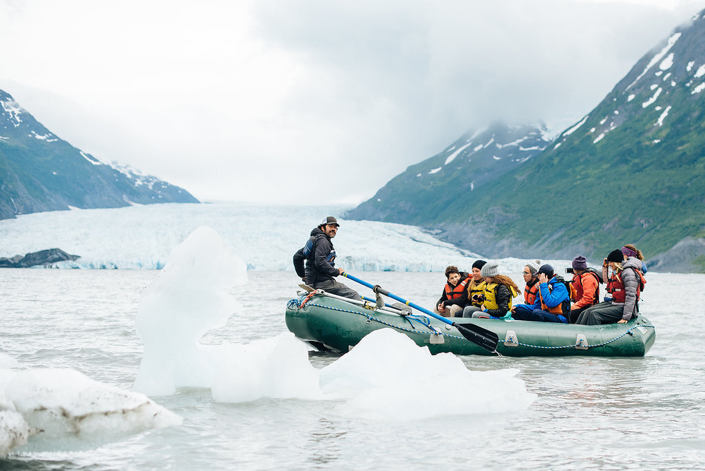  People in a raft looking at a glacier 