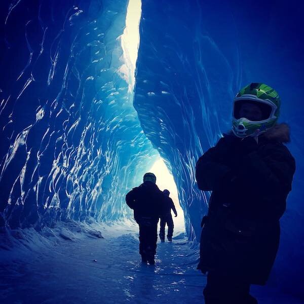  People walking into a glacier cave in the winter while Snowmobiling with Glacier City Snowmobile Tours 