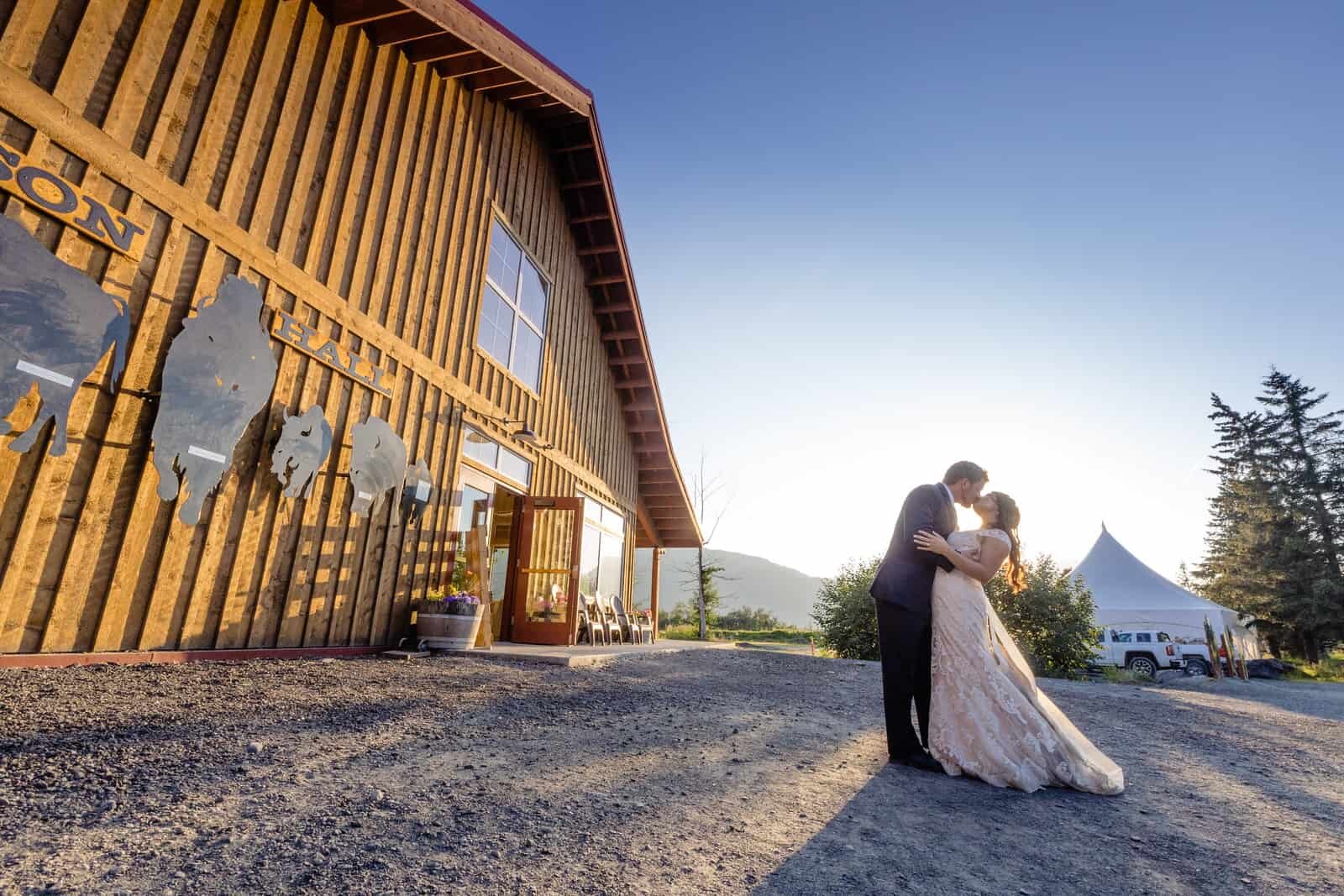  Bride and groom next to a building on Alaska Wildlife Conservation Center property 