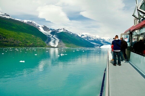  People standing on deck of Phillips Cruises looking at the water and glacier  