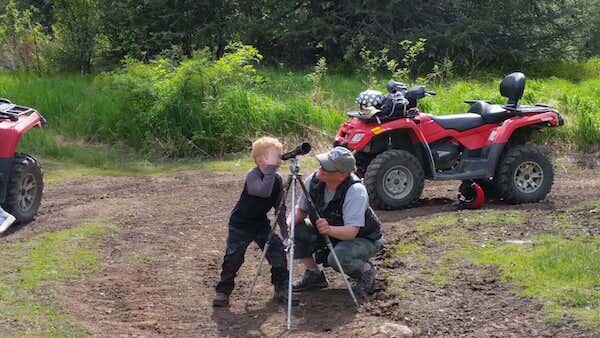  A young boy and father looking into a telescope at animals on a tour with Alaska Adventure 