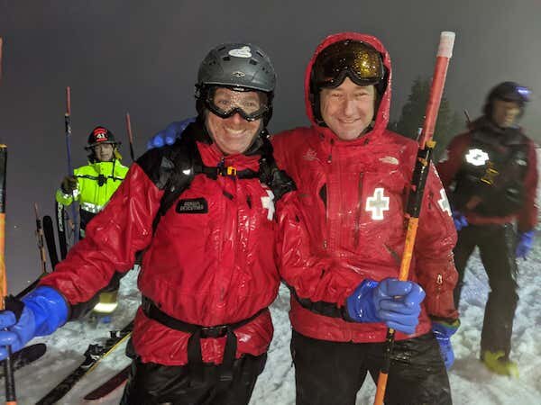  Two Ski Patrollers handing out flares at the beginning of the Torch Light Parade  