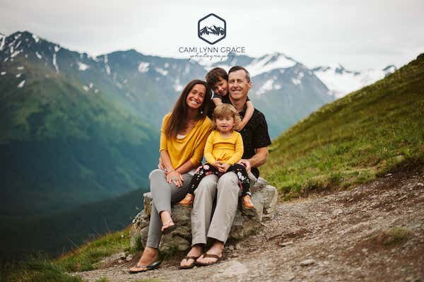  A family sitting on a rock with mountains in the background; photo taken by Cami Lynn Grace Photography 