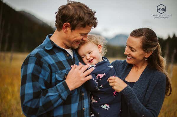  A family of three with a parents kissing the baby; photo taken by Cami Lynn Grace Photography 