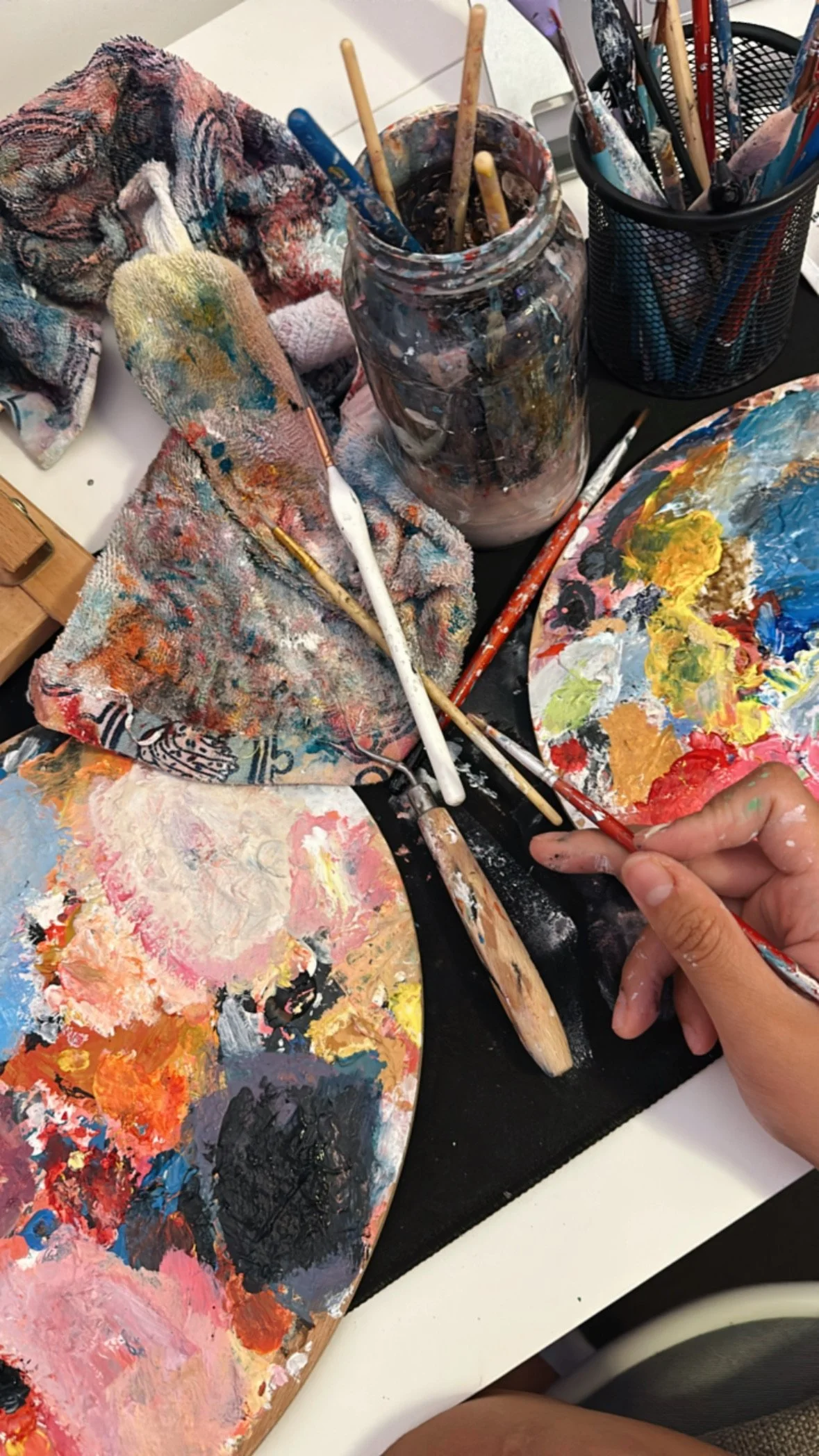 Messy art workspace with paintbrushes and colourful palettes: creativity, art therapy, mindful hobby.