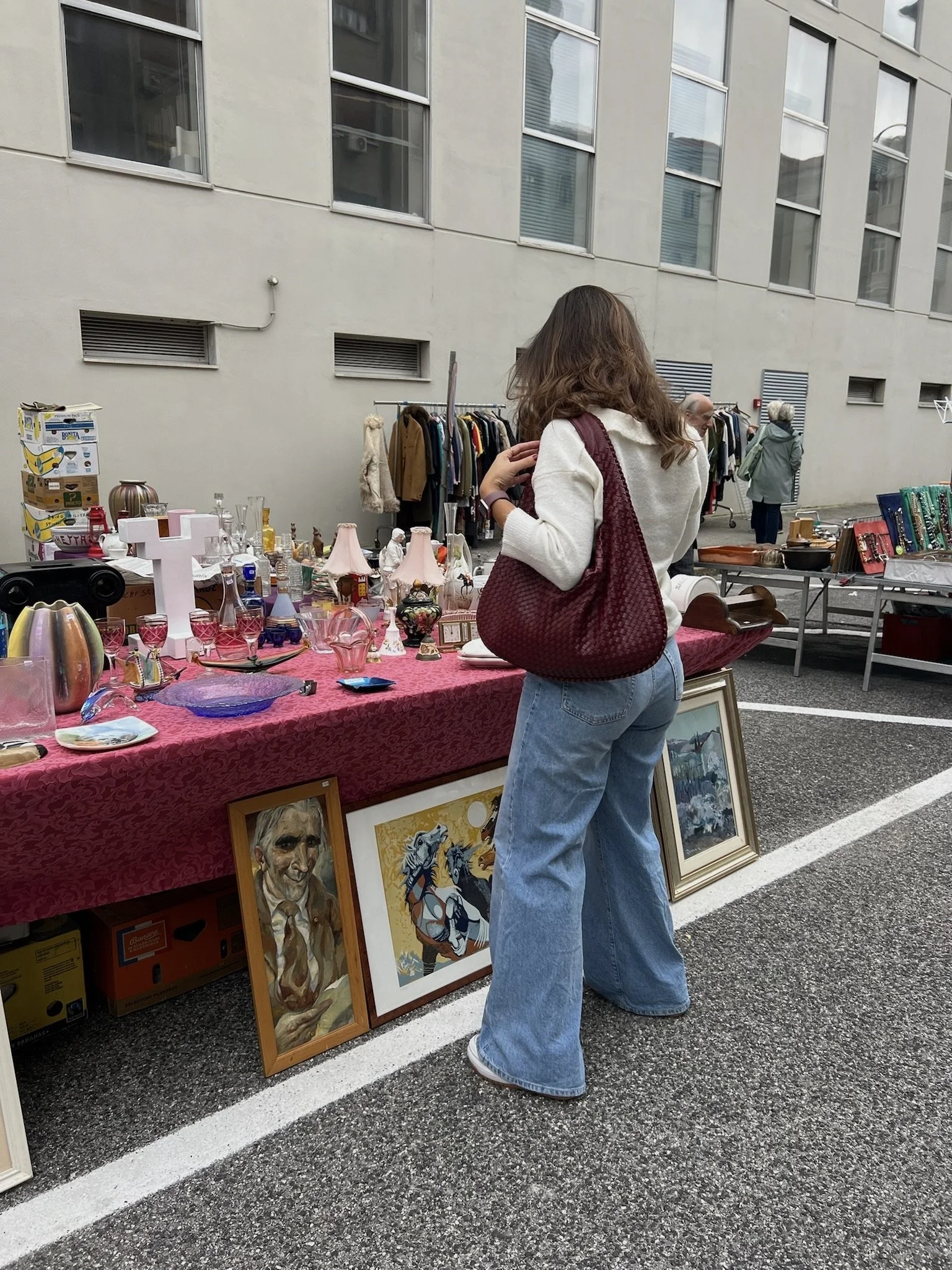 Woman browsing vintage art and decor at an outdoor market: slow living, weekend activity, window shopping aesthetic.