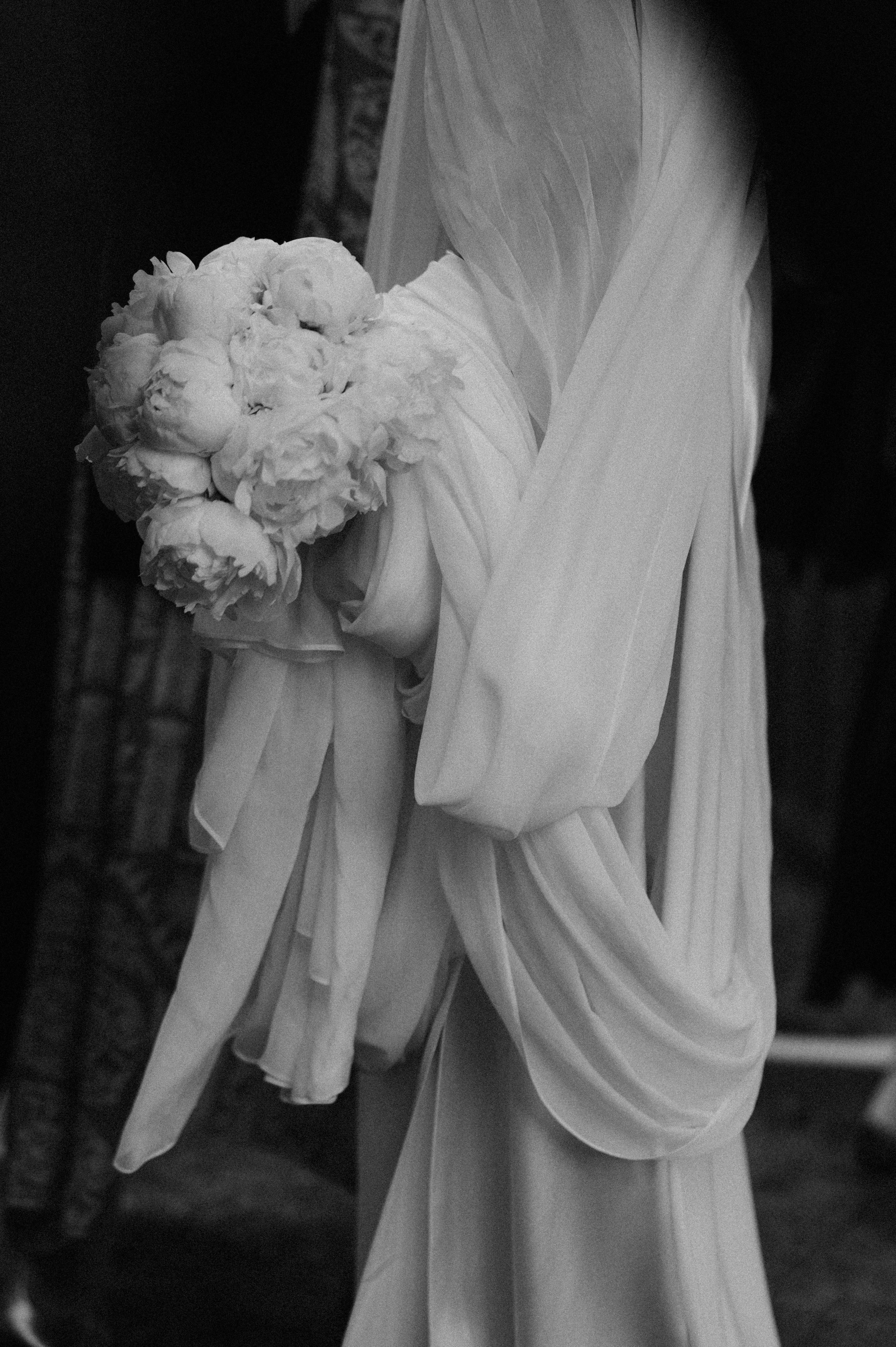 Une mariée avec son bouquet de pivoines et sa robe vaporeuse
