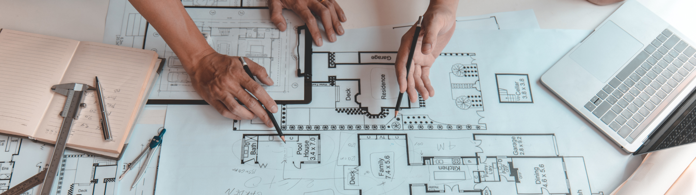 Permit professionals reviewing residential building plans and blueprints at a desk.