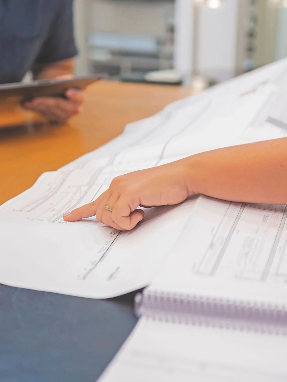 Person reviewing architectural drawings and construction plans for a building permit.