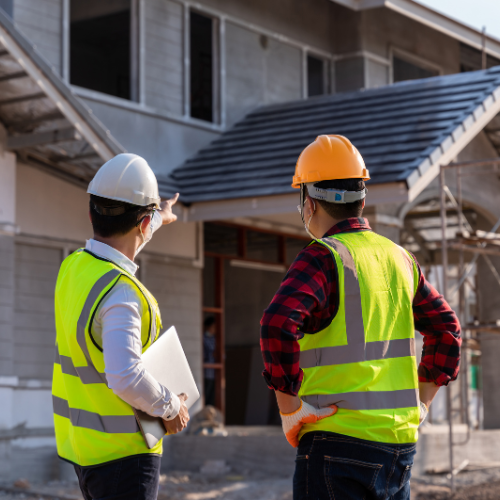 Two construction professionals reviewing progress at a residential building site.