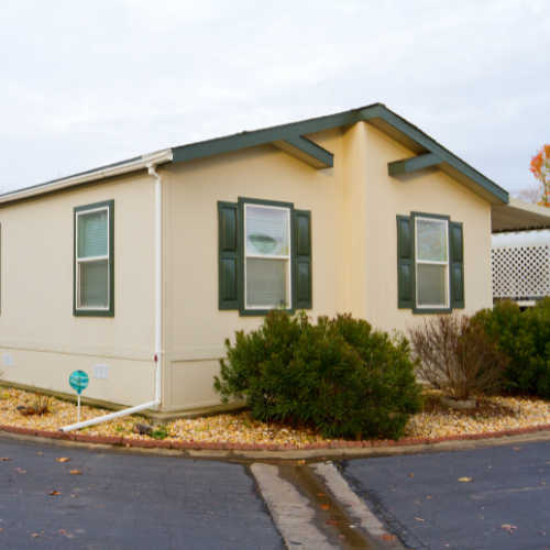 Exterior of a manufactured home with residential siding, windows, and landscaped surroundings.