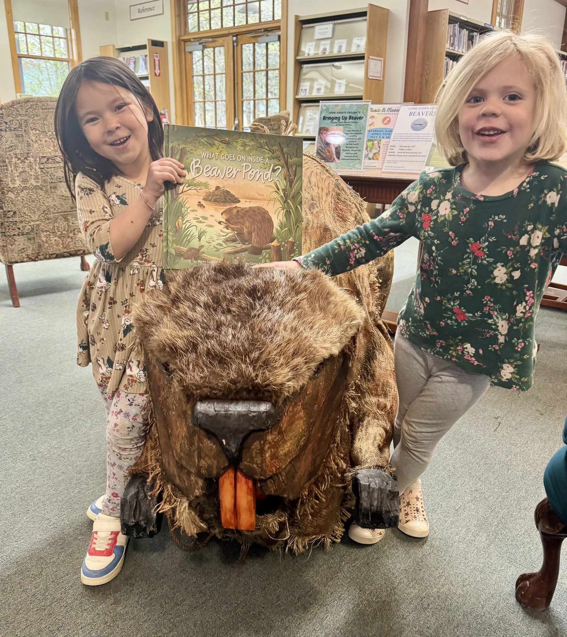 two young girls with crafted beaver and book