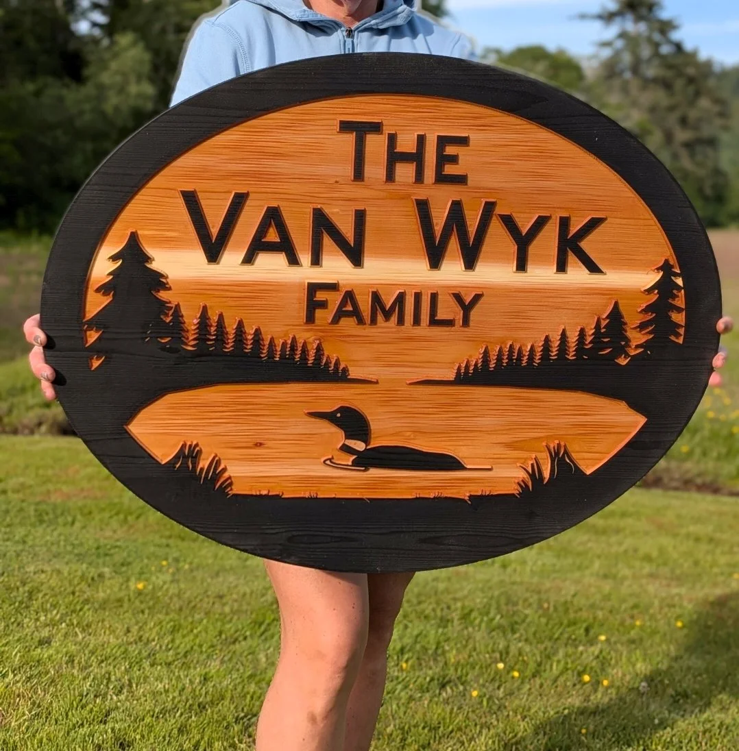 Personalized carved cedar sign with loon swimming on a lake and pine tree shoreline design, custom family name sign