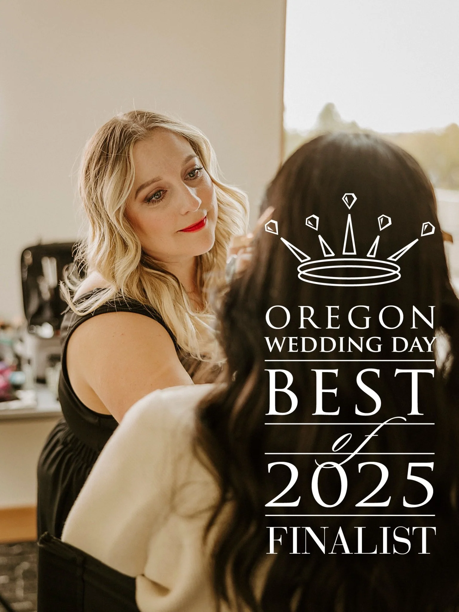 A woman with blonde hair and red lipstick is looking at another woman with dark hair, while applying makeup or styling her hair in a dressing room or backstage area. There is text on the image saying 'Oregon Wedding Day Best of 2025 Finalist' with a crown graphic.
