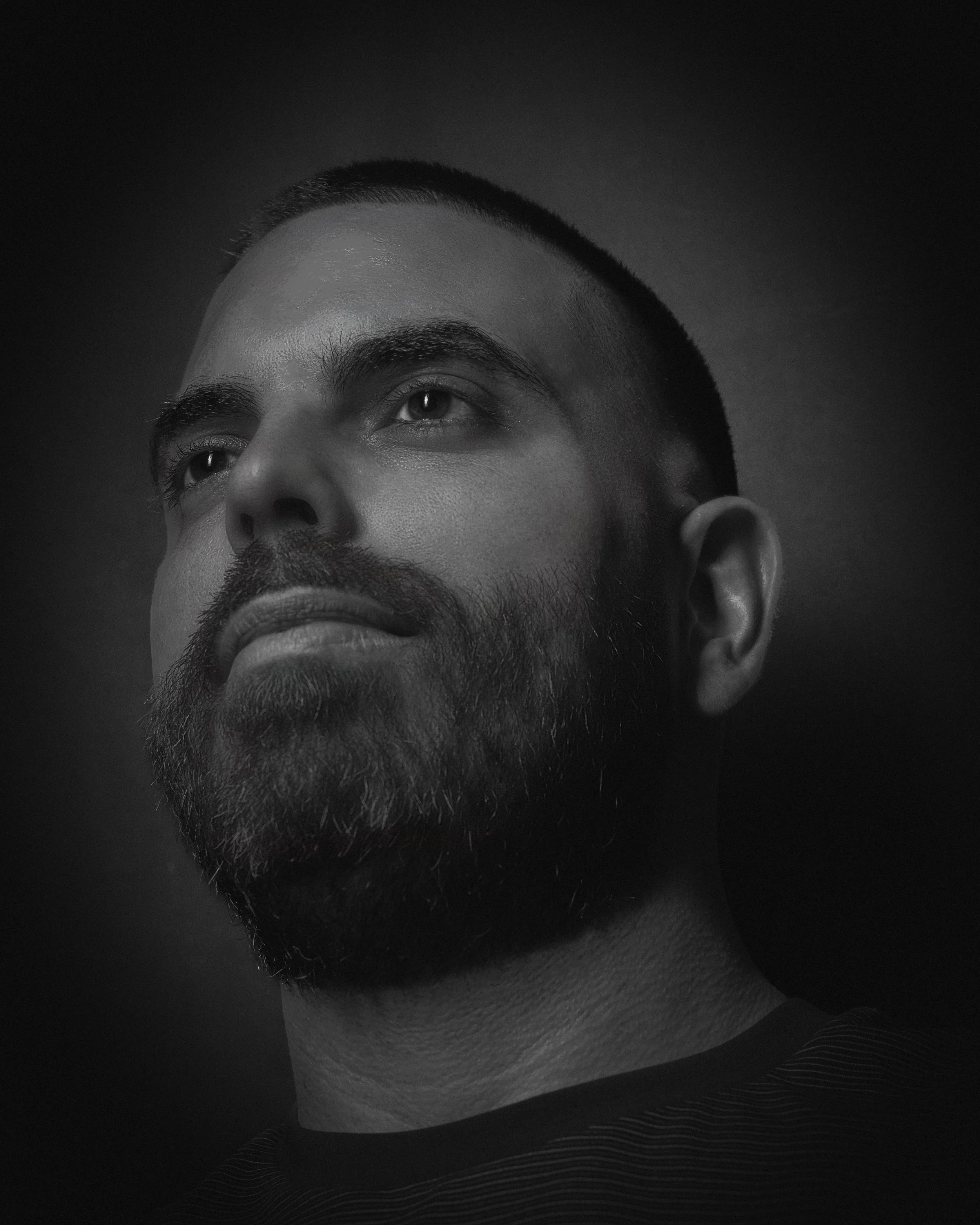 Black-and-white close-up portrait of Eduardo Aleman looking upward, photographed for portfolio work.