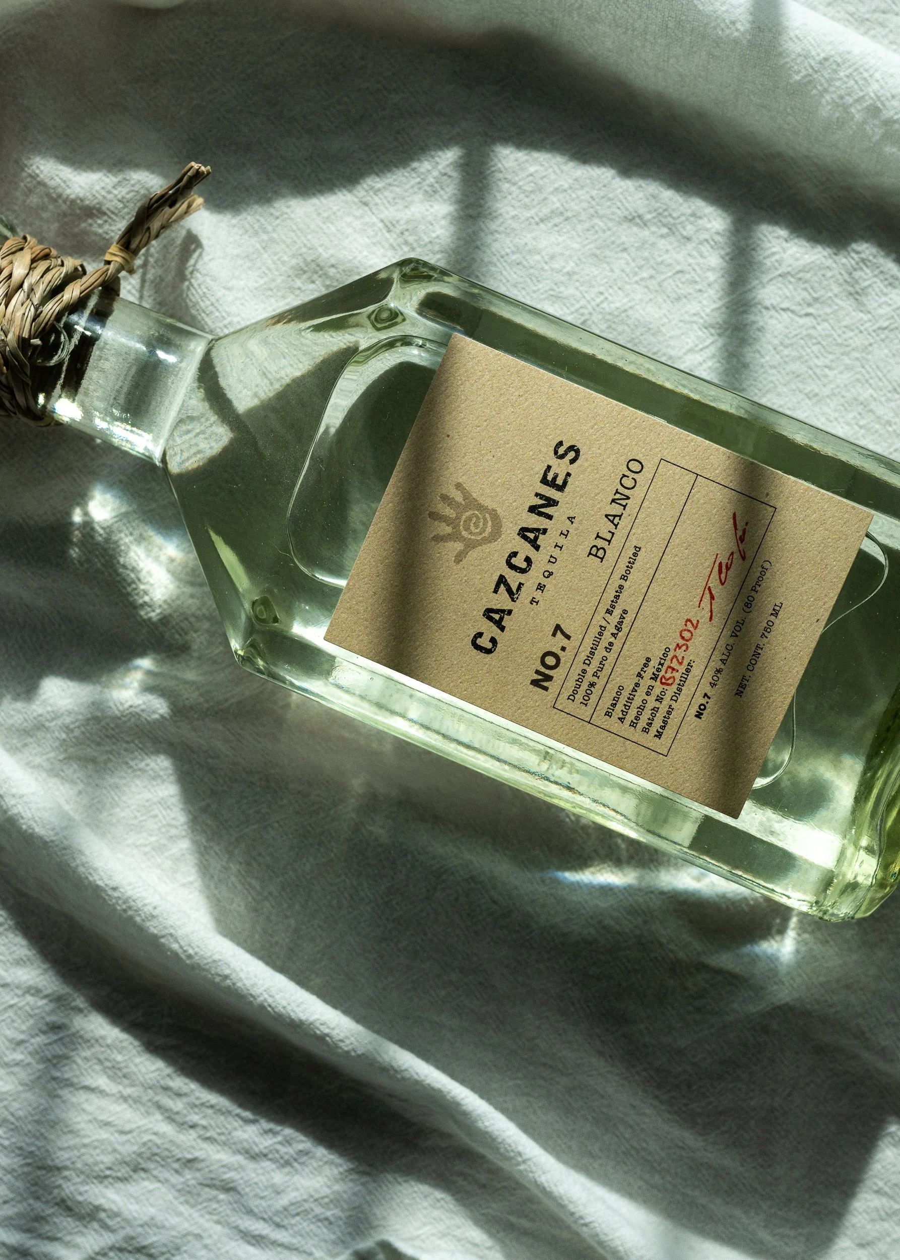 Elegant product photograph of Cazcanes Blanco Tequila, showcasing its artisanal bottle design and premium small-batch spirit, styled on a soft fabric backdrop.