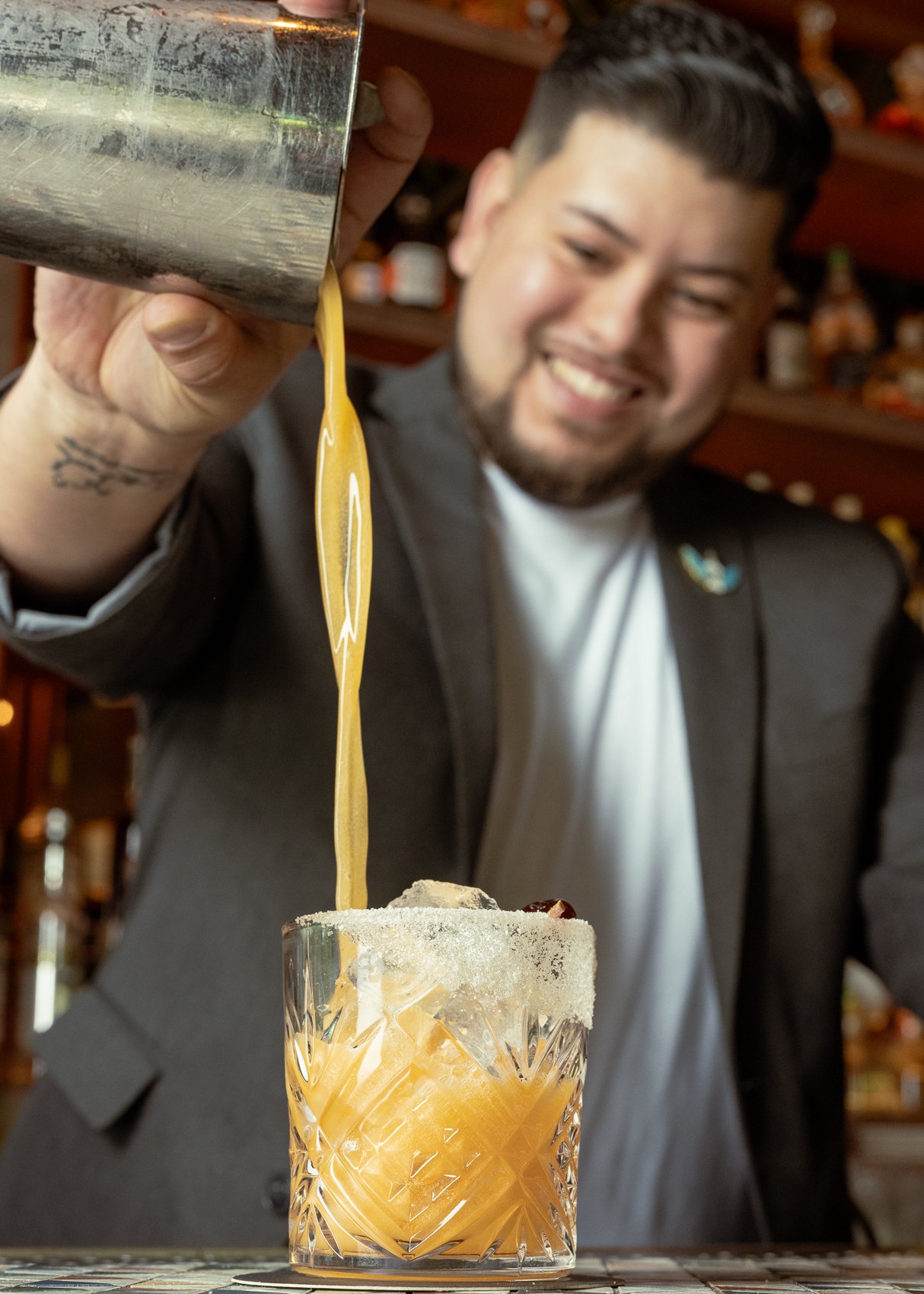 Bartender Fabio Crista pouring a golden cocktail into a rocks glass with ice, captured during a professional brand shoot for Avalon Vibes.