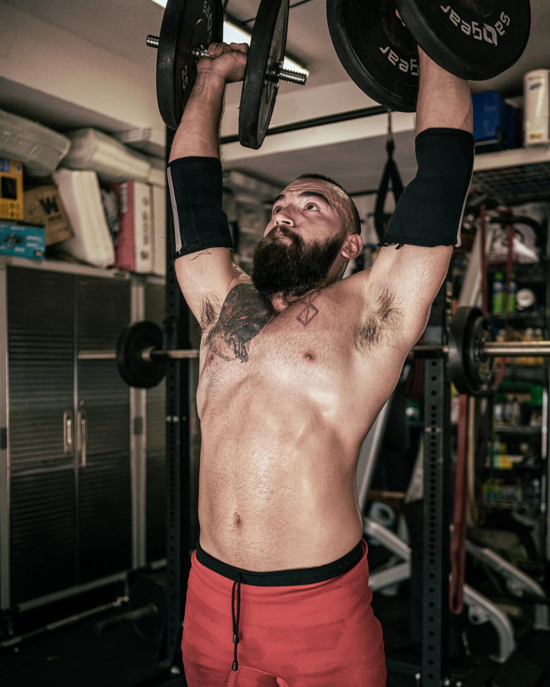 Esteban Cruz, strength and conditioning coach at Doral Academy and founder of Strength & Honor Fitness, performing an overhead dumbbell press during training.