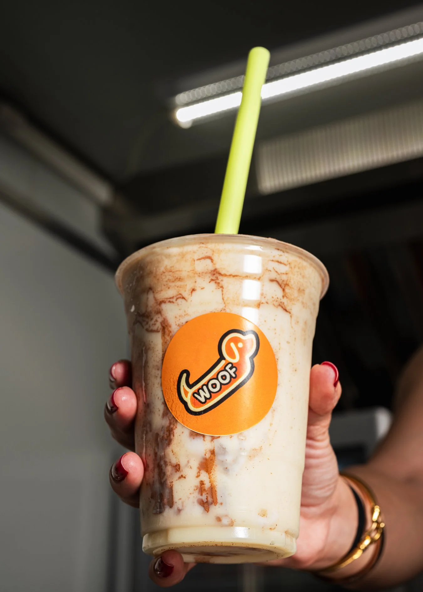 Traditional Venezuelan chicha rice drink served in iced branded Woof Hotdog cup, photographed for Woof Hotdog food truck in Doral.
