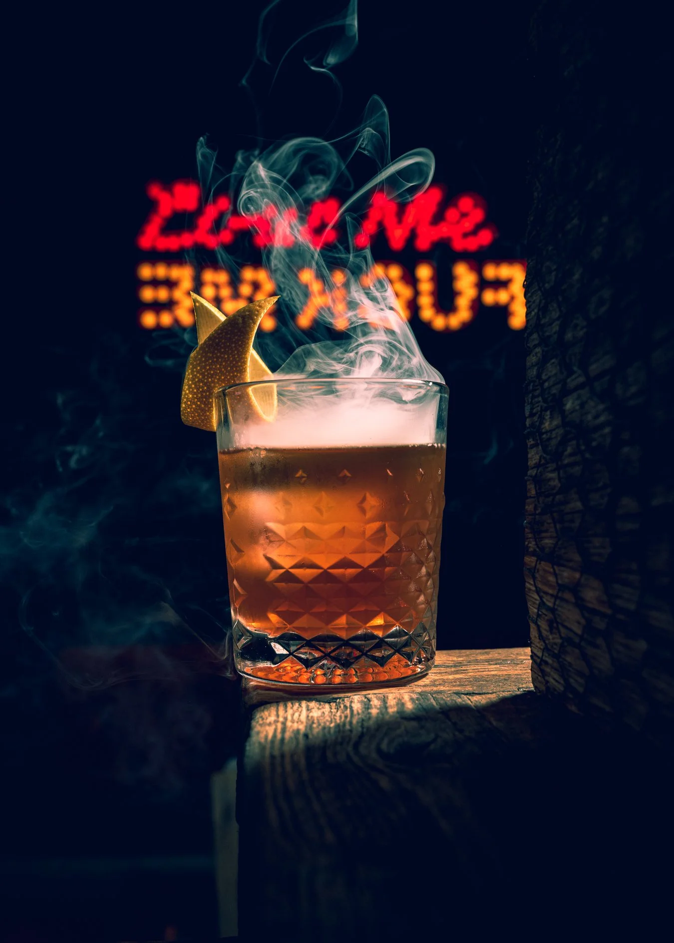 Smoked old fashioned cocktail garnished with an orange peel, photographed at Bodega Taqueria y Tequila in Coconut Grove with neon sign in the background.