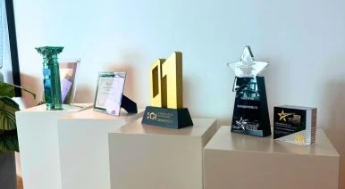 Display of various awards and trophies on white tables, including a gold number 1 trophy, a star-shaped trophy, and plaques.