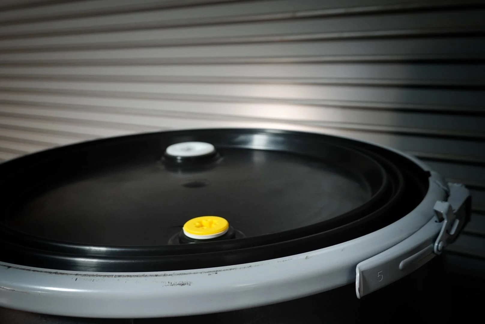 Close-up of a robotic vacuum cleaner on a surface with a louvered wall in the background