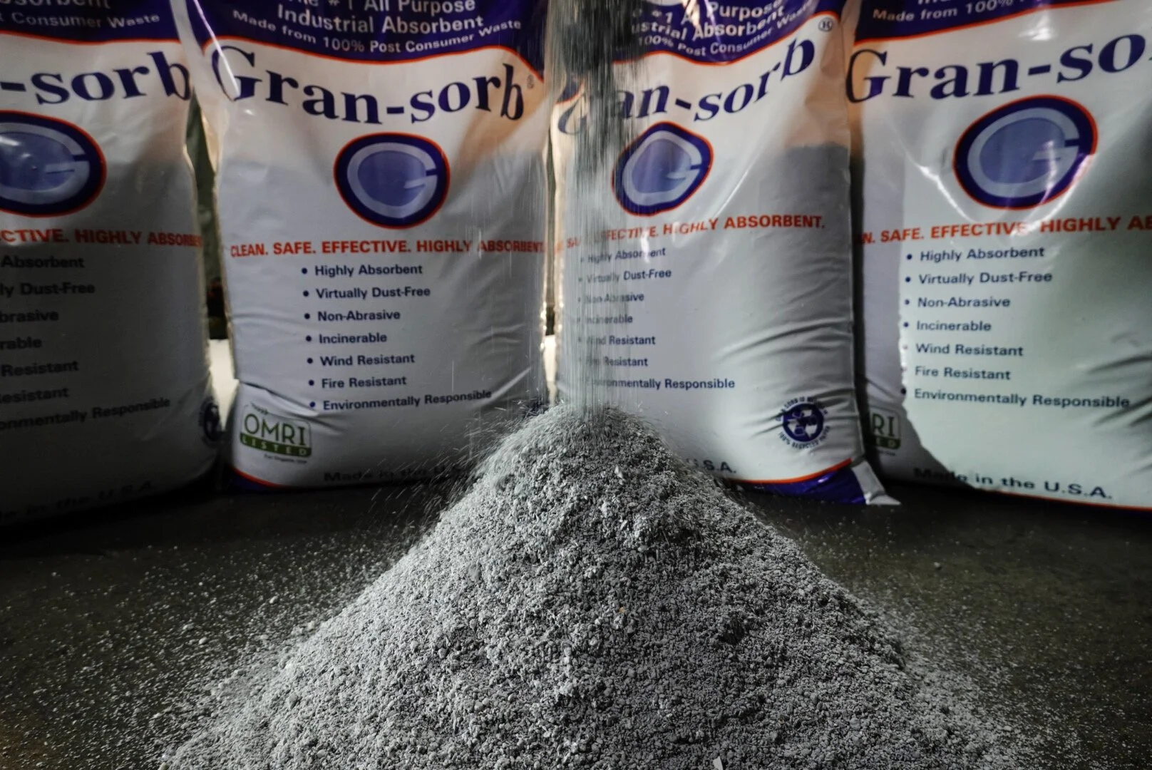 Three bags of granular absorbent powder labeled 'Gran-sorb' and a pile of the powder in front of the bags.