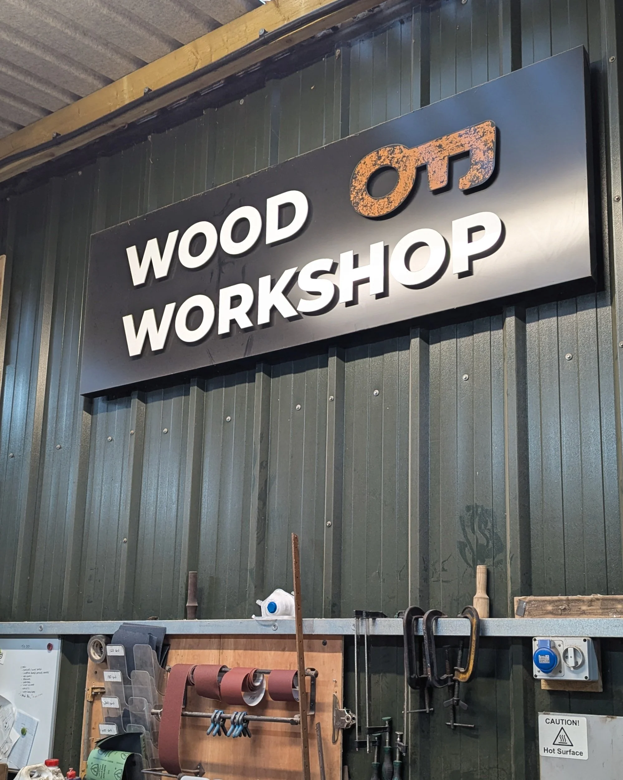 An interior view of the woodshop featuring a statement sign and an array of specialized tools used for shaping axe handles and fitting heads